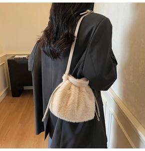 Detailed view of beige plush bucket bag with drawstring closure and leather strap