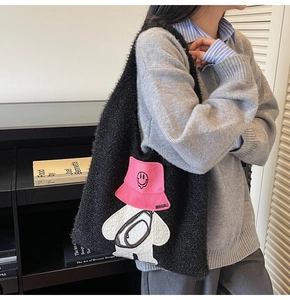Close-up of black fluffy plush hobo bag featuring a cute cartoon embroidery patch