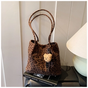 Detail of leopard print faux suede tote bag with a cute plush bear charm accessory