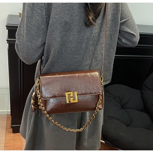 Macro shot of brown patent leather surface and golden metal logo on vintage crossbody bag