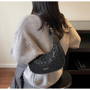 Detail view of the leopard print hobo bag with gold hardware and brand logo lettering
