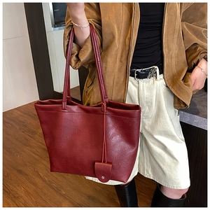Detail of burgundy faux leather tote bag with small coin purse charm and long shoulder strap