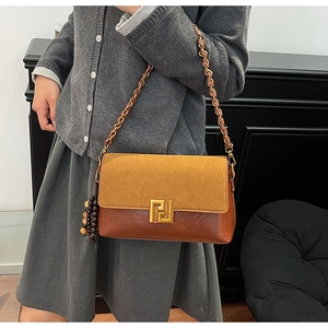 Detail of retro color-block shoulder bag with gold geometric buckle and wood bead tassel