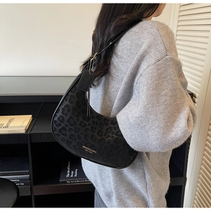 Close-up of leopard print hobo bag featuring gold brand logo and adjustable strap