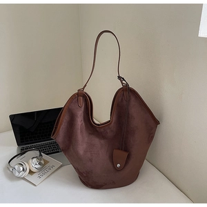 Vue détaillée d'un grand sac cabas en daim marron avec des anses en cuir sur un bureau