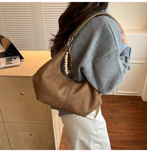Detailopname van bruine suède hobo tas met boheemse kralenkwast en zijaanzicht van de tas