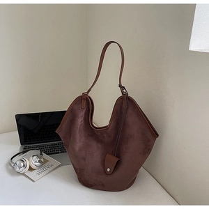 Détail du grand sac cabas en daim marron foncé avec bandoulière réglable et pendentif