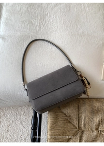 Detail of grey suede shoulder bag with retro wooden bead tassel on minimalist flap cover