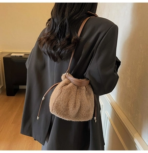 Detailed view of plush brown bucket bag with leather drawstring and metal charms