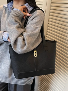 Grand sac cabas noir en cuir grainé avec boucle dorée et bandoulière porté par un mannequin