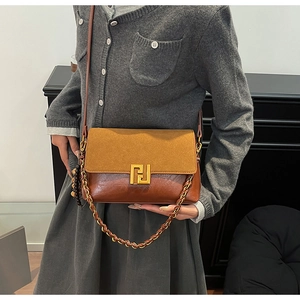 Detail of a brown and khaki shoulder bag featuring a large gold geometric metal buckle