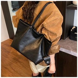 Side view of a black high-capacity tote bag with retro oily leather texture on a shoulder