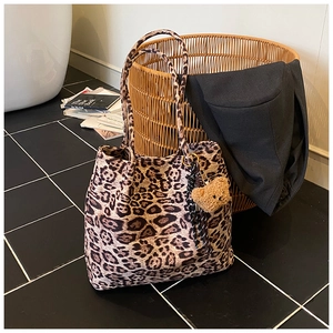 Detail of leopard print tote bag with brown plush bear charm and long shoulder handles