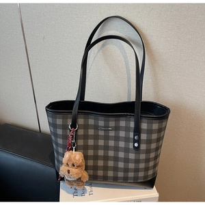 Macro shot of plaid tote bag featuring checkered pattern and plush dog charm with pearls
