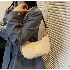 Detail of light beige leopard print crescent bag with brown trim and adjustable strap