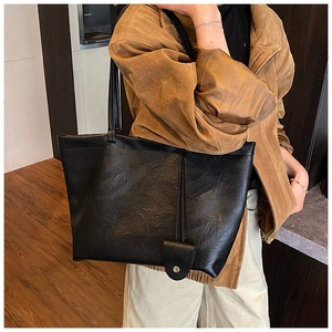 Macro detail of black vintage leather tote bag showing shoulder strap and side buckle