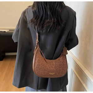 Detail of hobo crescent bag with leopard print and brown leather trim worn by model