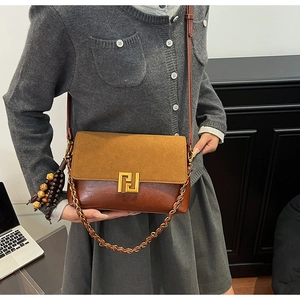 Close-up of vintage brown leather bag with gold geometric buckle and chain strap