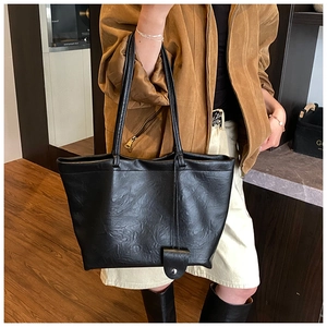 Detail of a large black vintage tote bag showing wrinkled leather texture and metal buckle