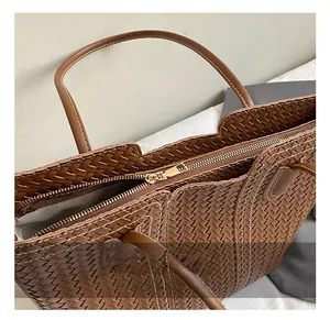 Detailed shot of brown woven tote bag with premium gold zipper and herringbone lining