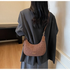 Detail of leopard print hobo bag worn by model with dark grey blazer in indoor setting