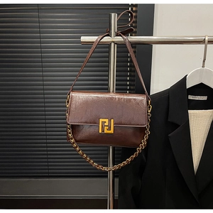 Detail of vintage dark brown faux leather shoulder bag with golden geometric metal buckle