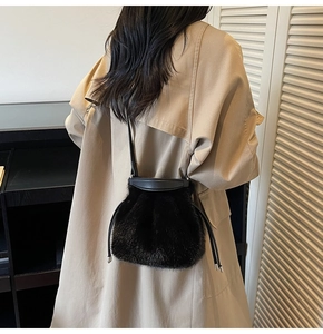 Detail view of the black faux fur bucket bag with drawstring closure on a khaki trench coat