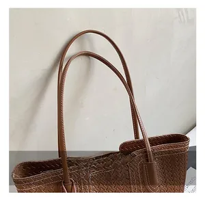 Detail shot of woven brown leather tote bag handle with high-quality stitching