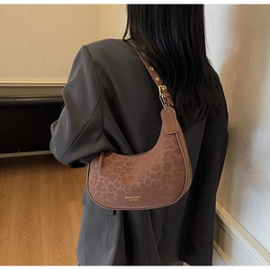 Detail showing brown leopard print texture and metal buckle on crescent shoulder bag