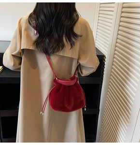 Detail of red faux fur bucket bag with drawstring and thin leather shoulder strap