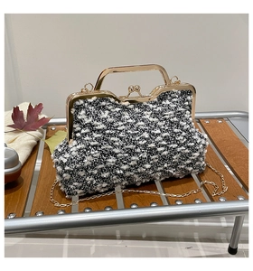 Détail d'un sac bandoulière vintage en tweed noir et blanc avec cadre doré et chaîne