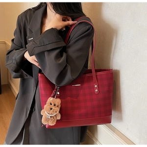 Detail of red checkered tote bag with a cute brown puppy plush charm and pearl chain