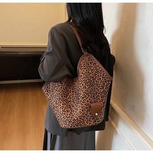 Détail du sac cabas léopard avec bandoulière en cuir marron et pendentif décoratif