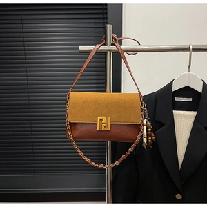Detail of vintage brown leather bag showing geometric gold clasp and wood bead charm