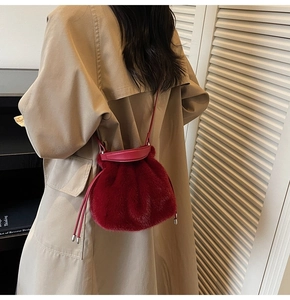 Detailed back view of a burgundy faux fur bucket bag worn with a beige trench coat