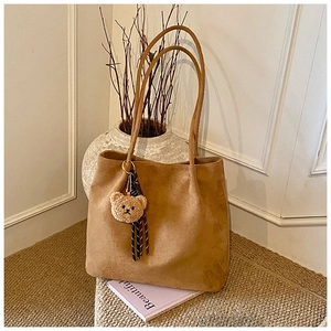 Brown suede tote bag detail with cute bear keychain and striped ribbon decor