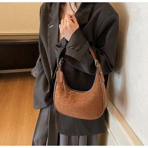 Detail view of leopard print crescent bag on a model wearing a grey blazer