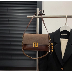 Detail of vintage brown suede shoulder bag with gold metal buckle and wooden bead charm