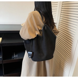 Detail of a large black suede tote bag with a soft matte texture and minimalist design