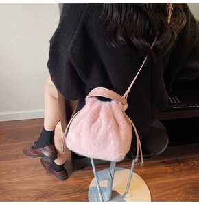 Close-up of pink faux fur bucket bag with drawstring closure and leather handle detail