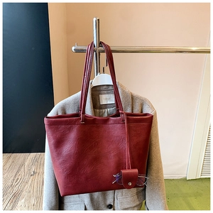 Detail of a dark red tote bag with leather texture and matching glasses pouch charm