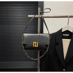 Close-up of retro black textured flap bag with a striking gold geometric metal clasp