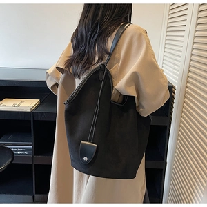 Détail du grand sac cabas noir en daim mat avec ouverture incurvée et fine bandoulière