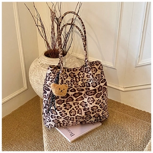 Close-up of leopard print tote bag with brown plush bear charm in vintage setting