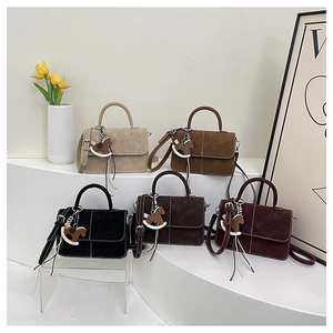 Detailed display of five stylish suede handbags with elegant pony charms and silk scarves