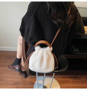 Detail of white faux fur bucket bag featuring brown leather drawstrings and strap