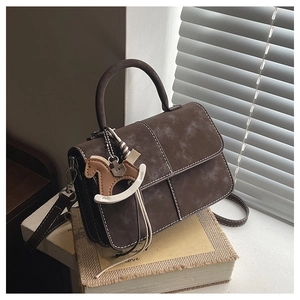 Detail view of dark brown vintage crossbody bag with contrast stitching and horse charm