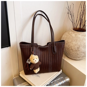 Close-up of dark brown woven tote bag texture with a cute teddy bear charm