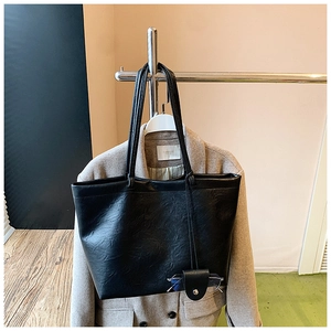 Detail of a black pebbled leather tote bag with a small matching hanging accessory pouch