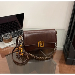 Detail of vintage oil wax leather bag with golden buckle and wooden bead tassel